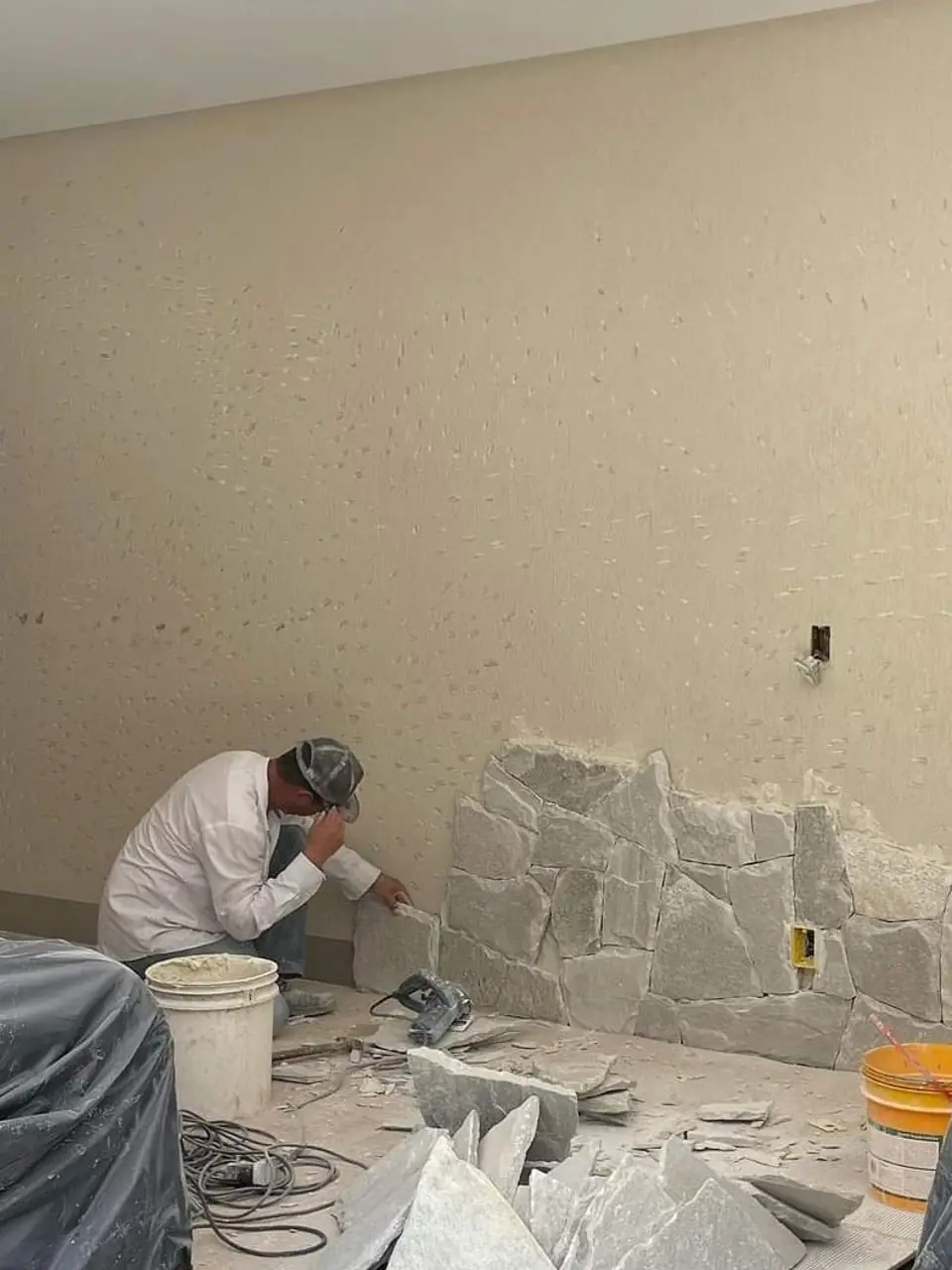 Profissional da equipe assentando revestimento de pedra em uma parede durante a obra