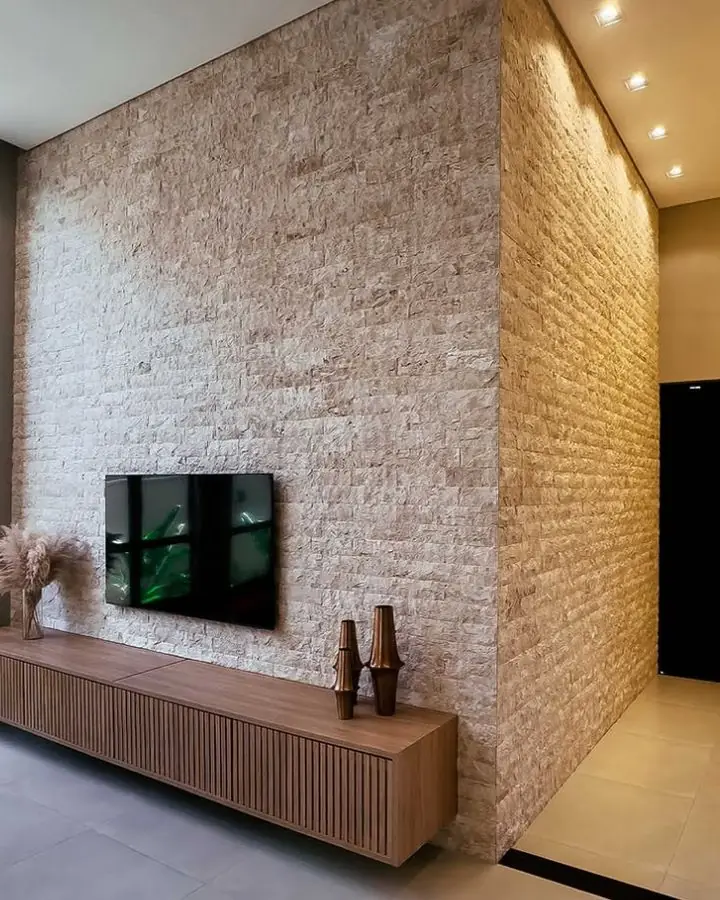 Home theater com parede revestida em pedra natural clara