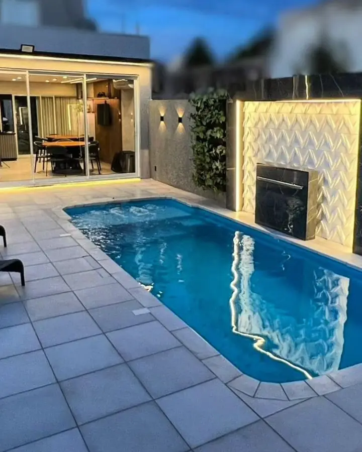 Área de piscina iluminada à noite com cascata revestida