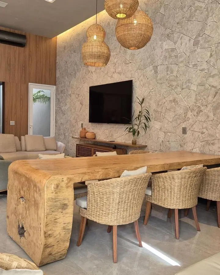 Sala de estar com parede revestida em pedra natural e mesa de madeira maciça