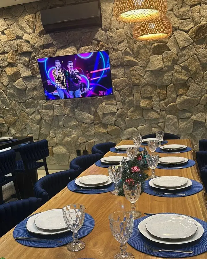 Sala de jantar com parede em pedra rústica e iluminação embutida