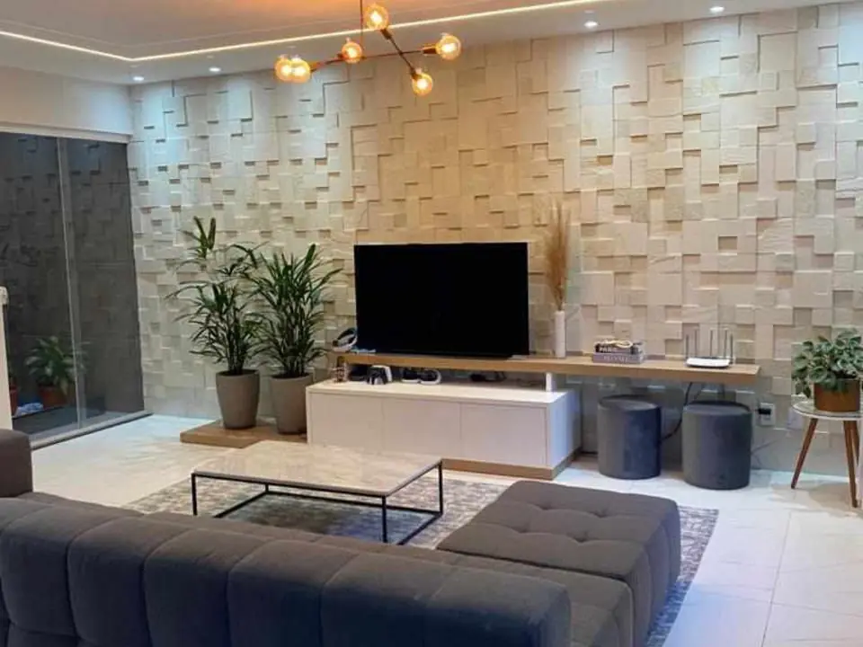 Sala de estar com parede revestida em placas de pedra em relevo, executada pela Pedras da Terra