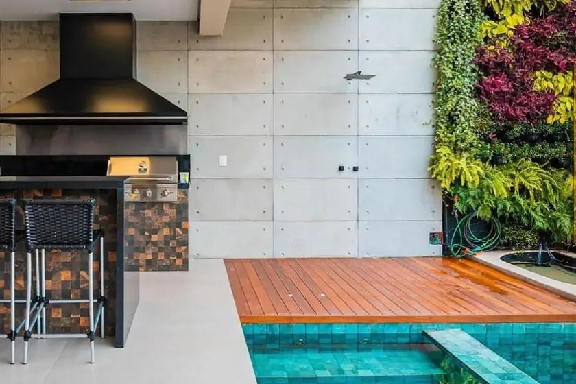 Área gourmet com piscina, jardim vertical e parede revestida